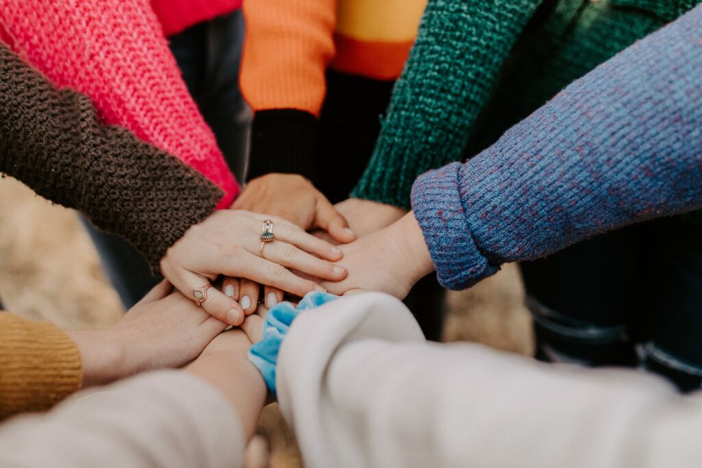 A group of people's hands together in the centre of a circle.